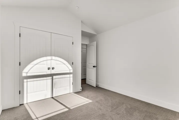 White walls, carpeted flooring, and a standard interior door