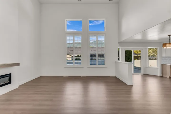 Vaulted ceiling with a wood-finish flooring, featuring a linear electric fireplace with a floating mantel