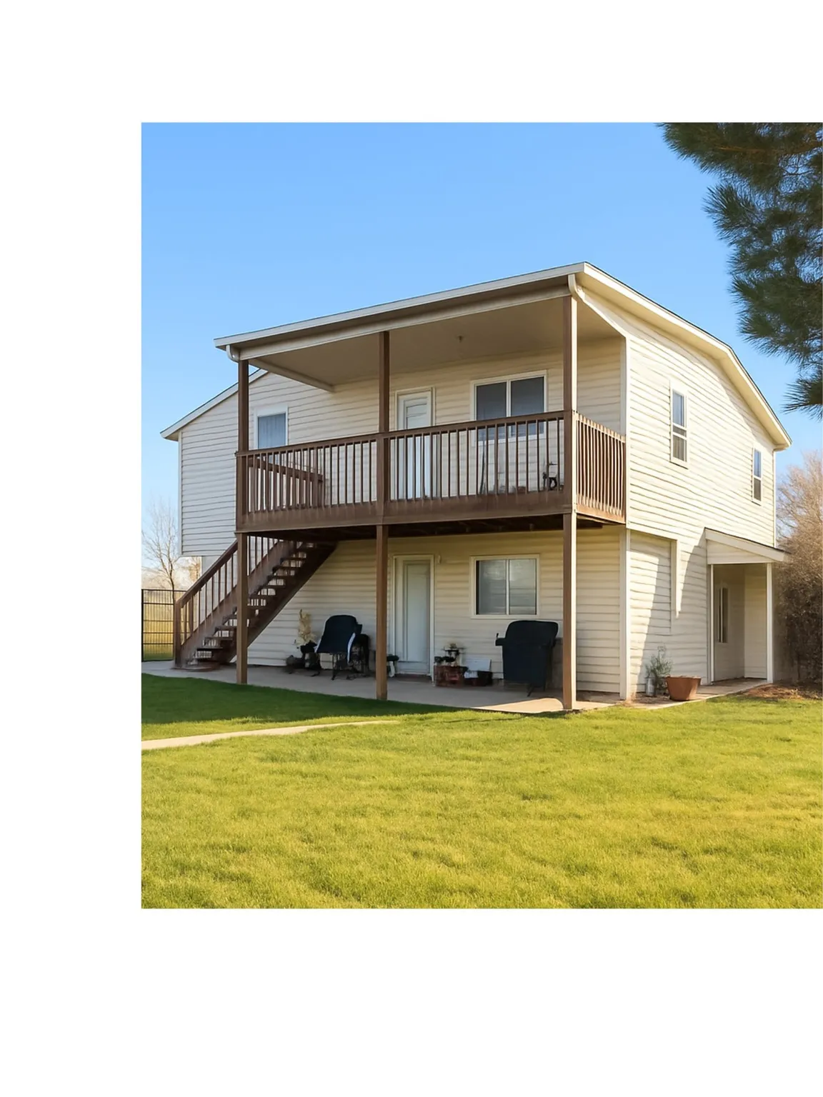 Two-story residence featuring siding exterior, an upper-level covered deck with wood railings, and a lower-level patio