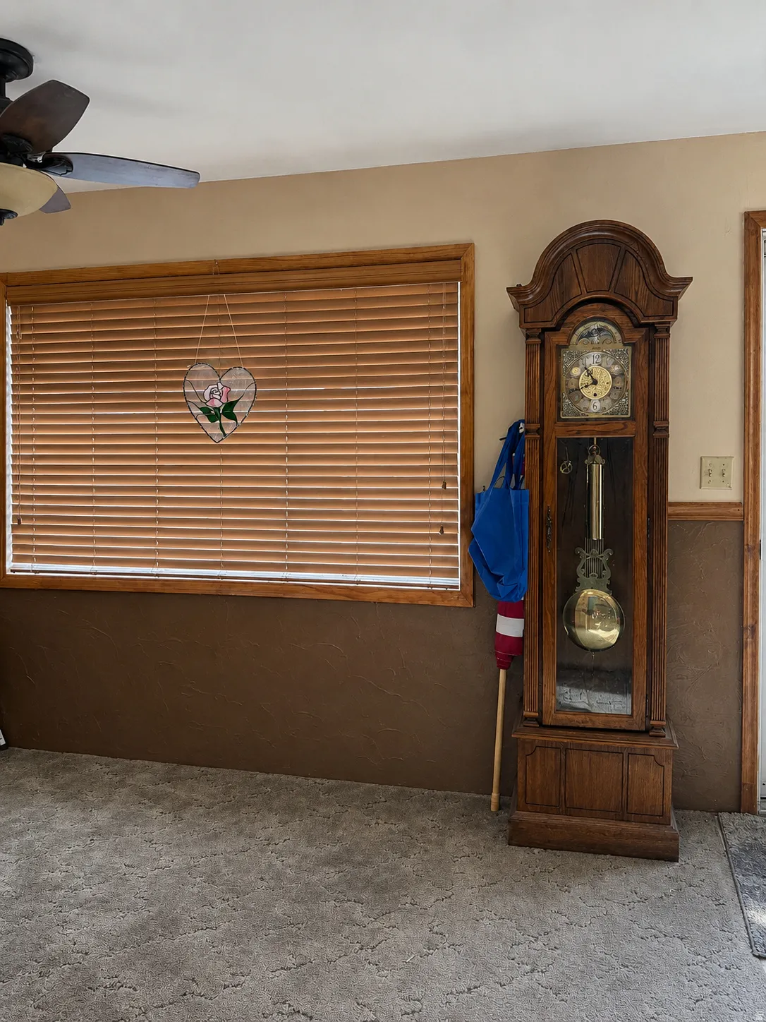 Window with wood-finish blinds and trim, textured wall finishes, and ceiling fan with integrated lighting