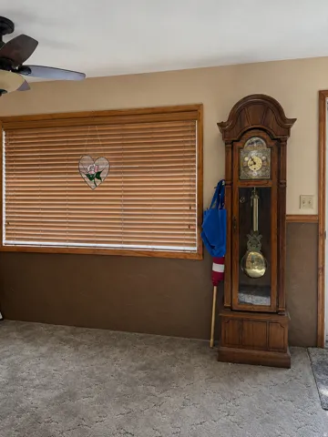 Window with wood-finish blinds and trim, textured wall finishes, and ceiling fan with integrated lighting