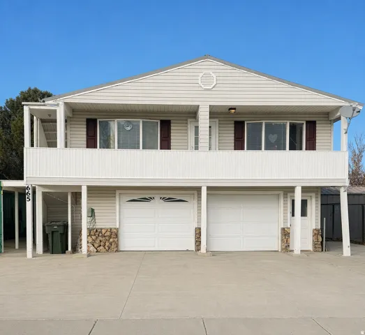 Siding exterior with a gable roof, featuring a second-story balcony and two garage doors