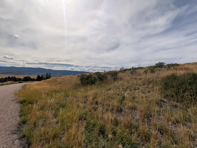 Gravel road access with natural landscaping, featuring distant mountains and a broad sky