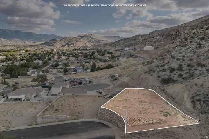 Mountainous terrain with a graded building pad, established street, and stone retaining wall
