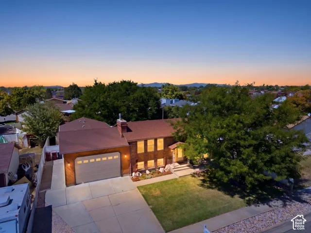 Front view of the home with an extra-large driveway, extra parking, 10' tall garage doors, an extra-height garage, a shaded front patio, and a fully fenced backyard with multiple gates for access.