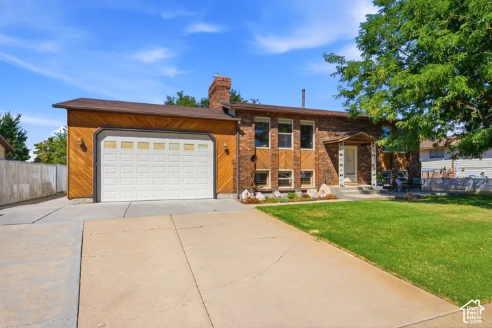 Front view of the home with an extra-large driveway, extra parking, 10' tall garage doors, an extra-height garage, a shaded front patio, and a fully fenced backyard with multiple gates for access.