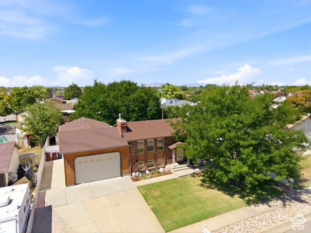 Front view of the home with an extra-large driveway, extra parking, 10' tall garage doors, an extra-height garage, a shaded front patio, and a fully fenced backyard with multiple gates for access.