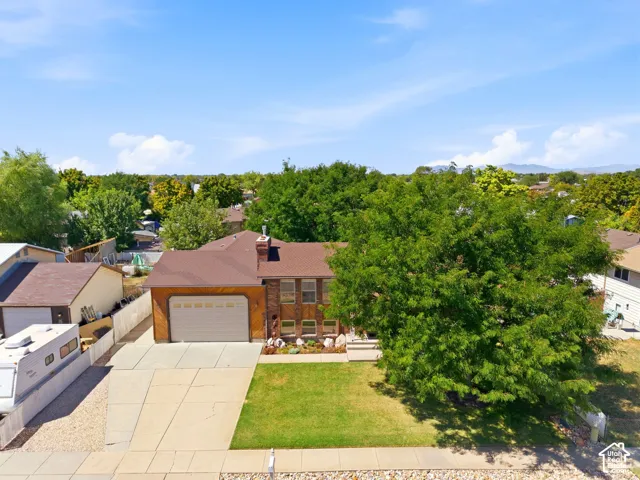 Front view of the home with an extra-large driveway, extra parking, 10' tall garage doors, an extra-height garage, a shaded front patio, and a fully fenced backyard with multiple gates for access.