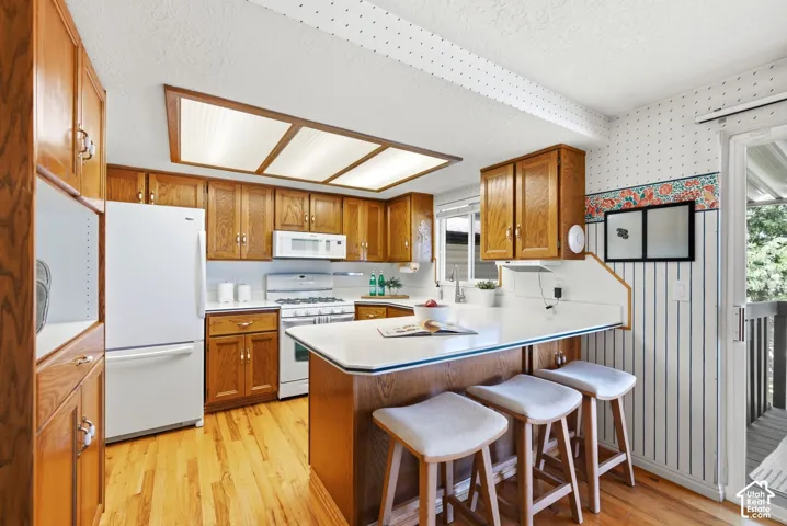 Kitchen featuring wood cabinetry, light wood-finish flooring, with bar seating, and a sliding glass door to the back deck and access to the yard.