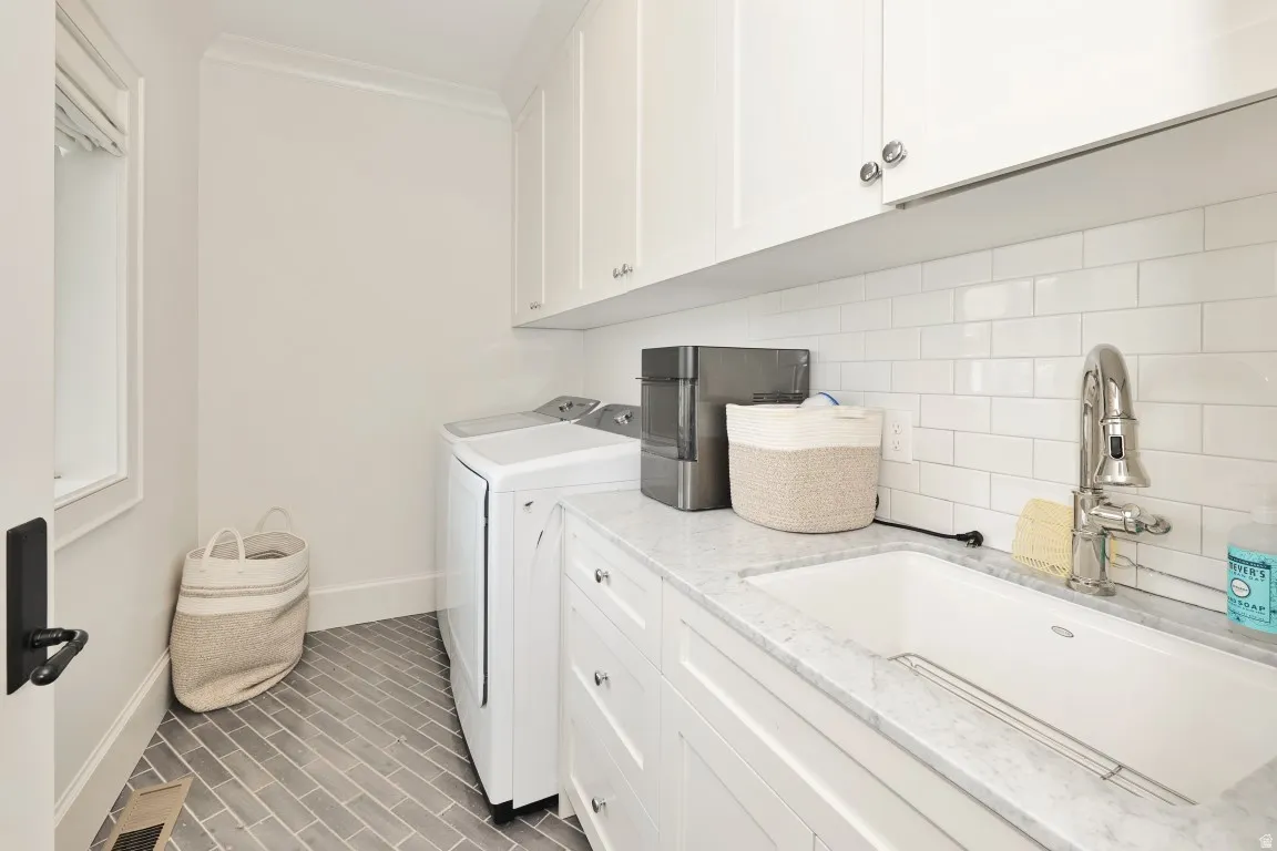 White subway tile backsplash, white shaker-style cabinetry, undermount sink, countertop, and herringbone tile flooring