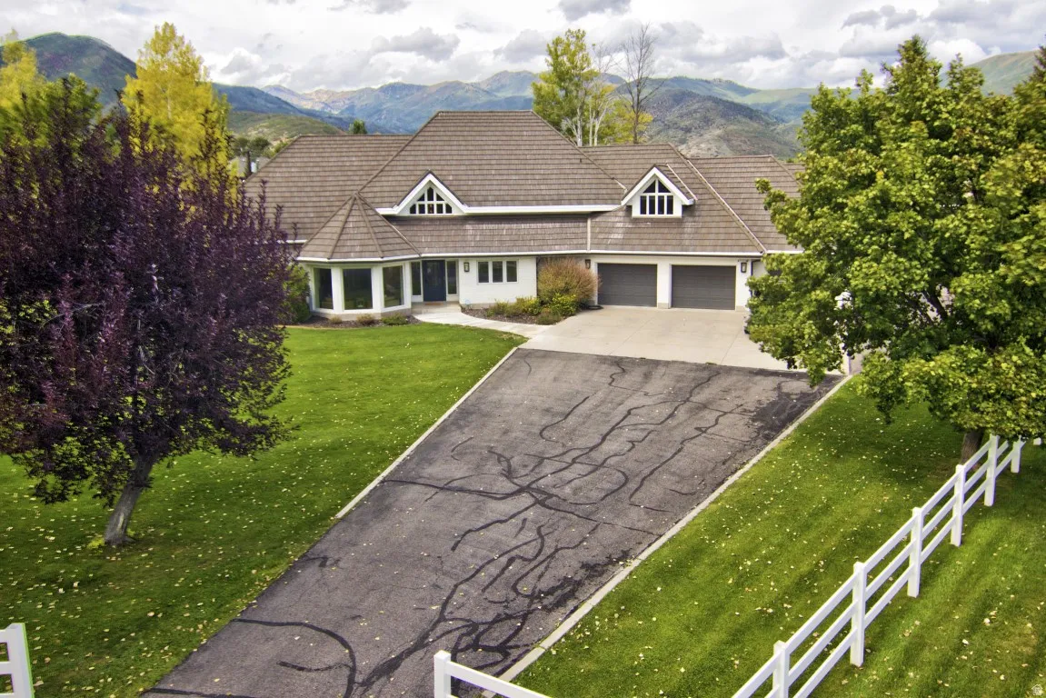 Gable roofline with dormer windows, two-car garage, bay windows, and a manicured lawn