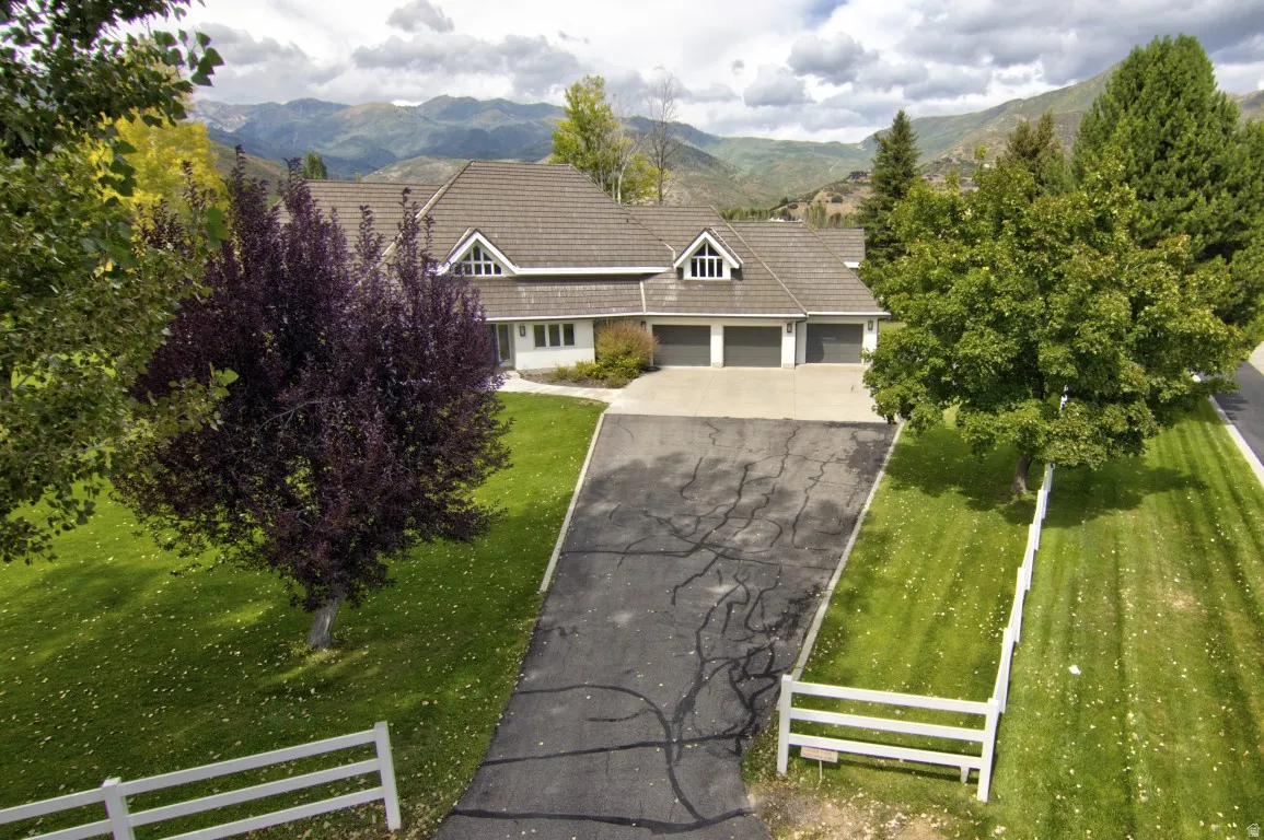 Expansive dwelling with a shingled roof, multiple dormer windows, and a three-car garage