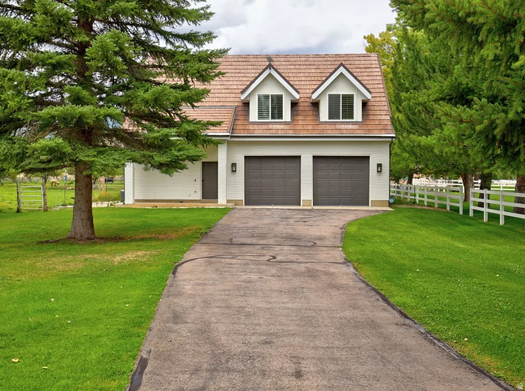 White exterior with two dormer windows, a wood-shingle roof, and a two-car garage