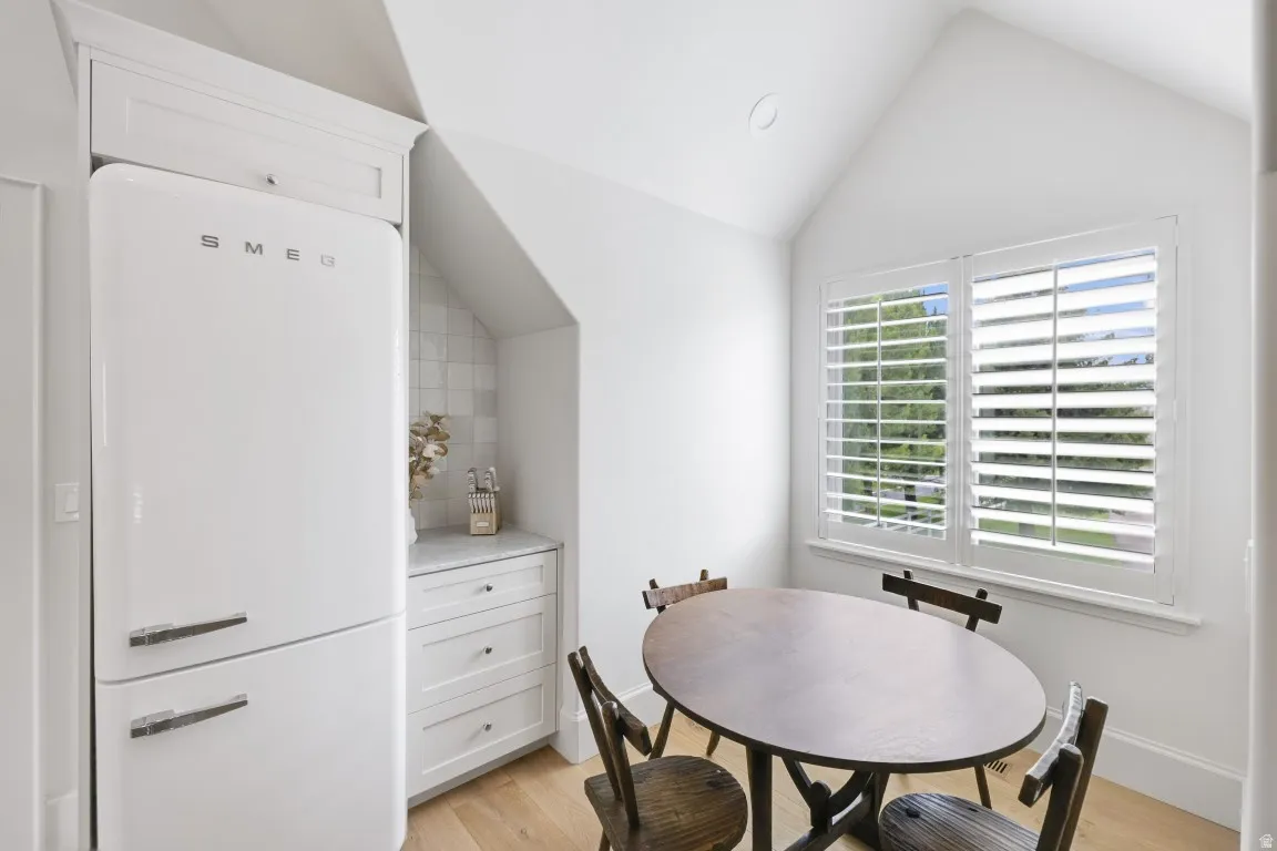 Vaulted ceiling with recessed lighting, wood-finish flooring, built-in cabinetry with stone countertop, and plantation shutters