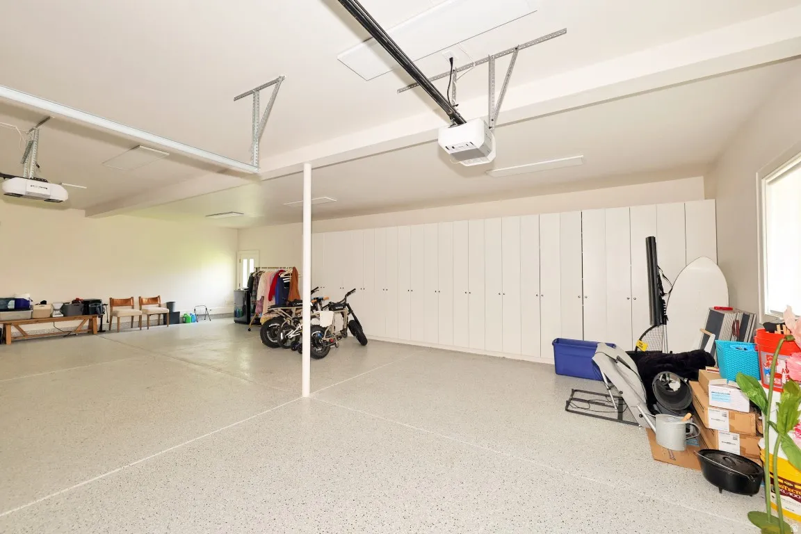 Expansive garage space with epoxy flooring, recessed lighting, and extensive built-in cabinetry for storage