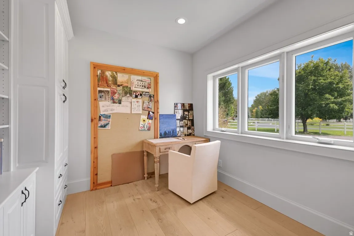 Light wood-finish flooring with white baseboards, bright white trim, and recessed lighting