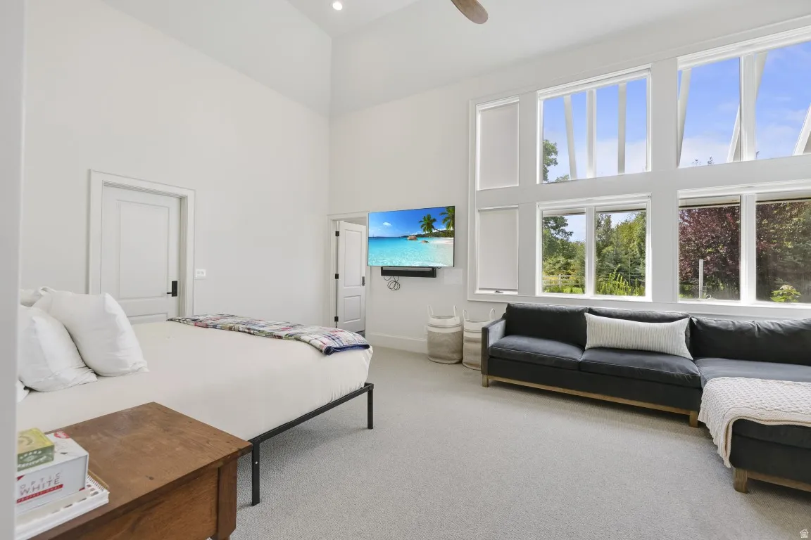 Vaulted ceilings with recessed lighting, expansive multi-pane windows, wall-mounted television, and light-toned carpeting