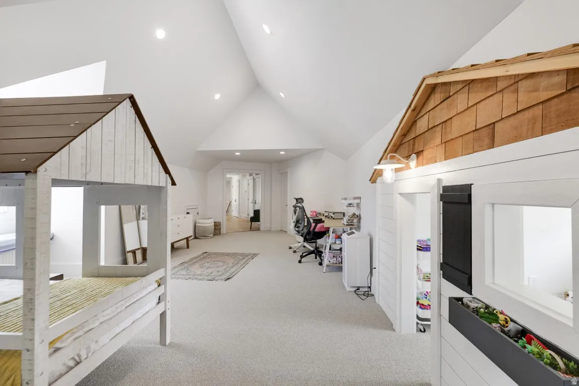 Vaulted ceiling, recessed lighting, and light-toned carpeting
