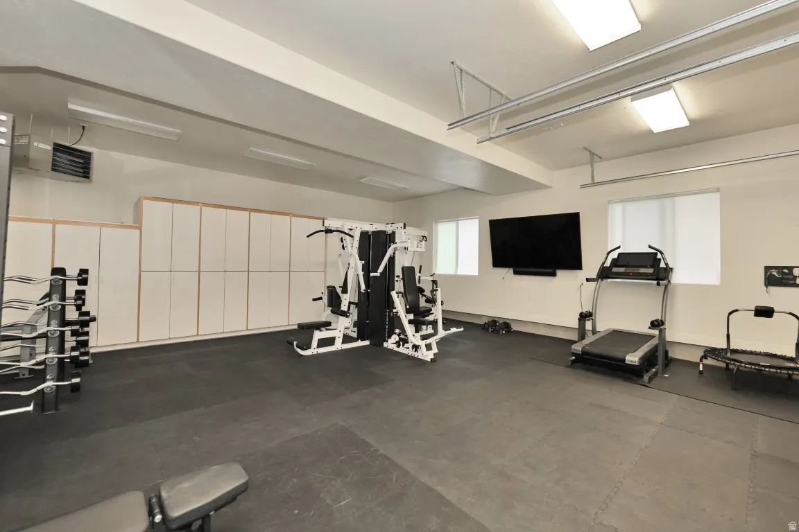 Dedicated fitness area featuring extensive built-in storage, durable rubber flooring, and multiple windows
