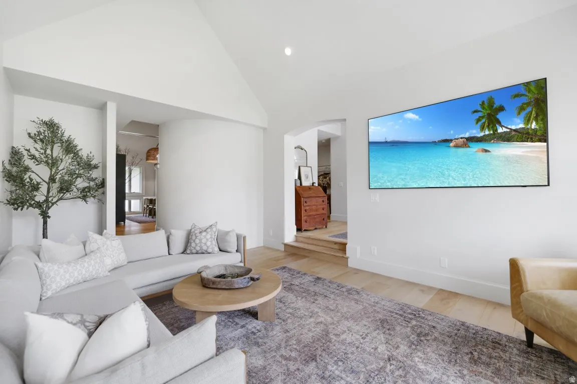 Vaulted ceiling with recessed lighting, light wood-finish flooring, and white painted walls
