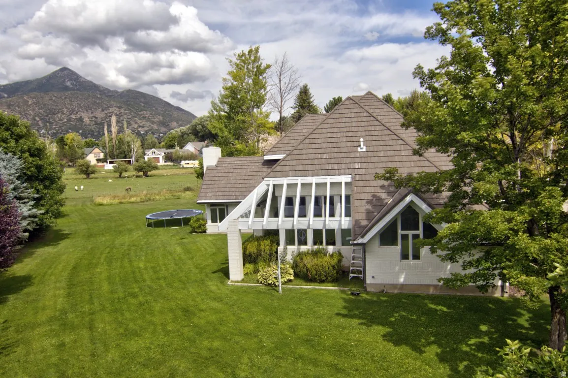 Expansive green lawn with mature trees and a prominent mountain backdrop