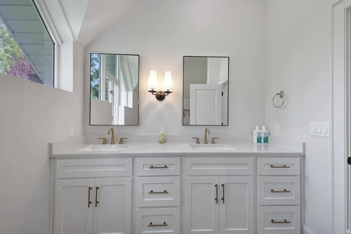 Dual vanity with white cabinetry, bronze hardware, and rectangular undermount sinks