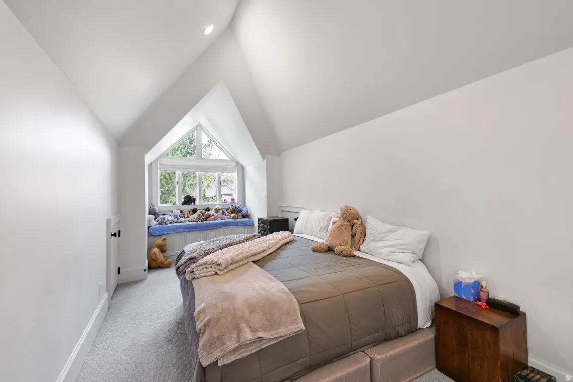 Vaulted ceiling with recessed lighting, angled walls, and light-colored carpeting