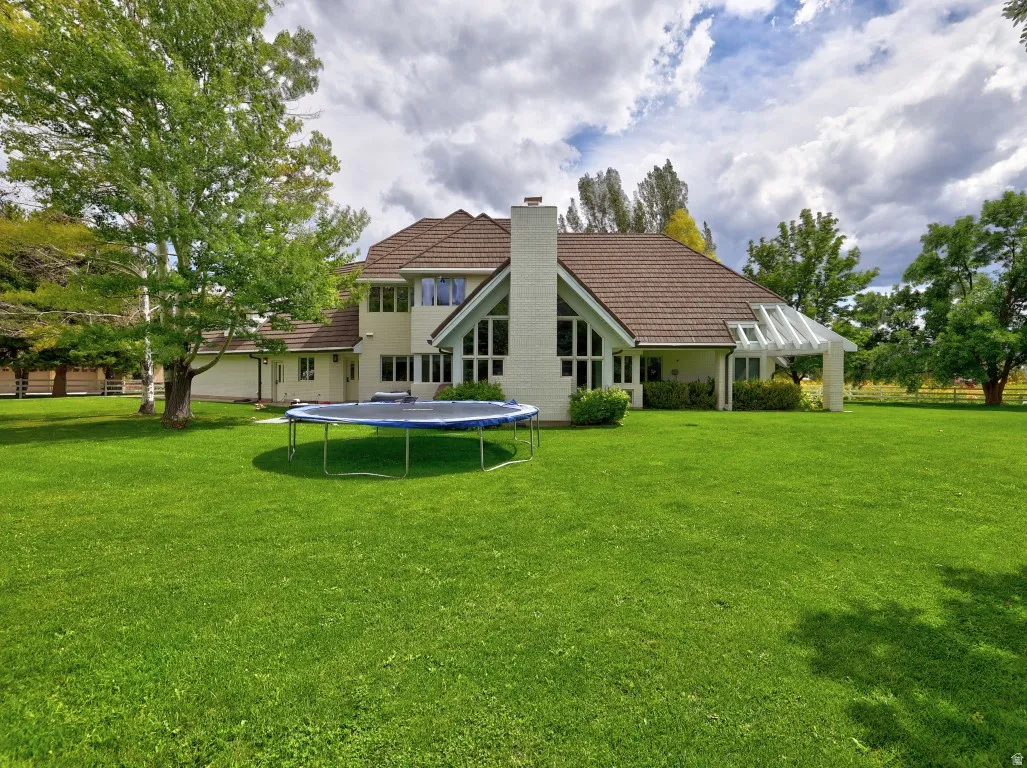Expansive green lawn with mature trees and a stucco exterior featuring a gabled roof