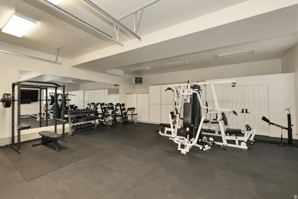 Dedicated fitness space featuring wall-to-wall mirrors, built-in cabinetry, and recessed ceiling lighting
