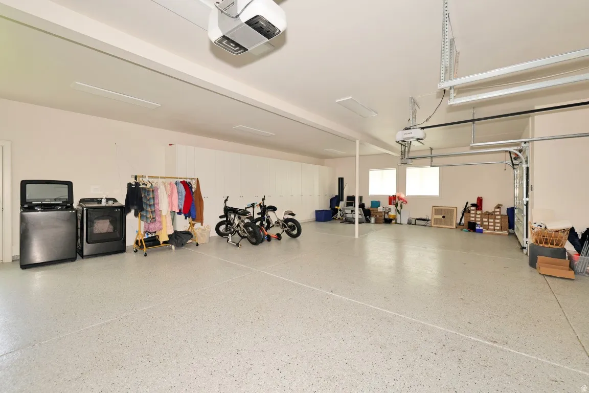 Spacious garage featuring an epoxy floor, multiple windows, and overhead lighting