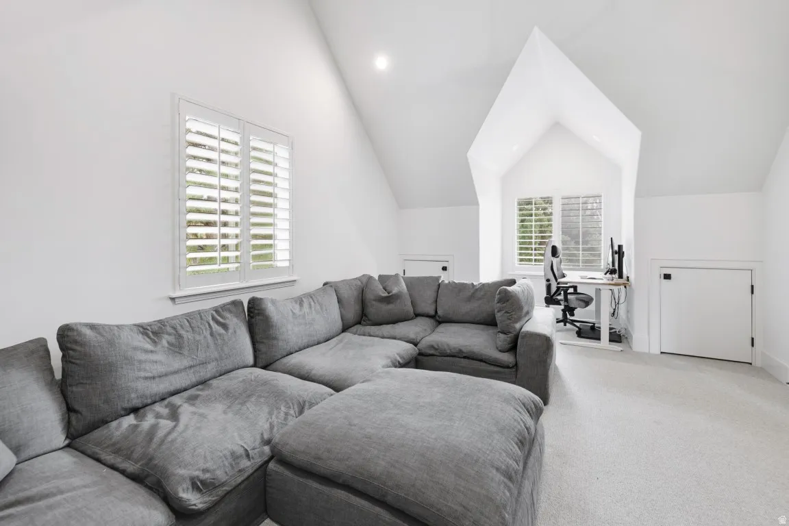 Vaulted ceiling, two windows with plantation shutters, recessed lighting, and light-toned carpeting