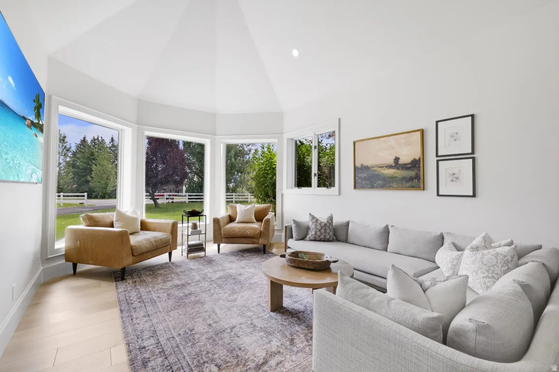 Vaulted ceiling, recessed lighting, wood-finish flooring, multiple large windows, and a built-in wall-mounted television