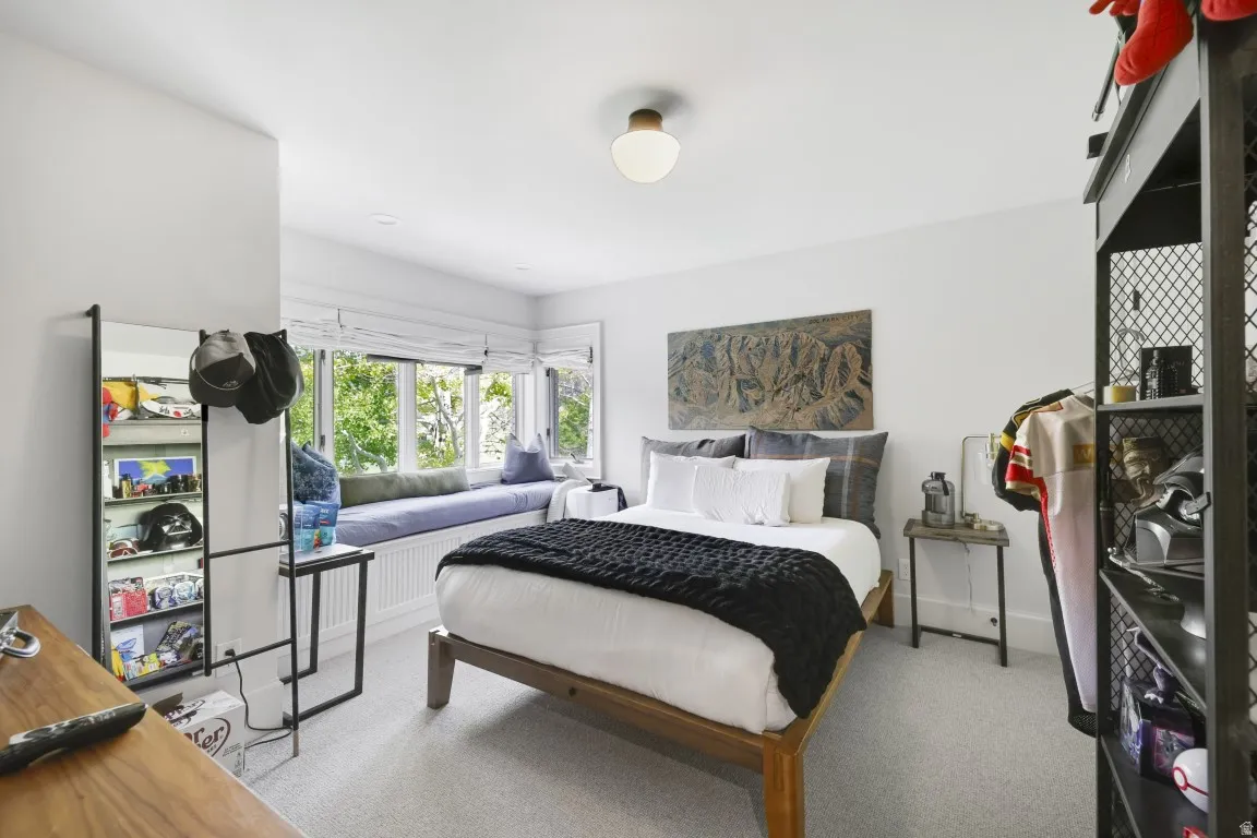 Recessed lighting, wood-frame bed, window seat, neutral wall paint, and carpeting