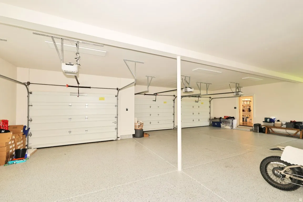 Three-car garage featuring automatic garage door openers and an epoxy-coated floor