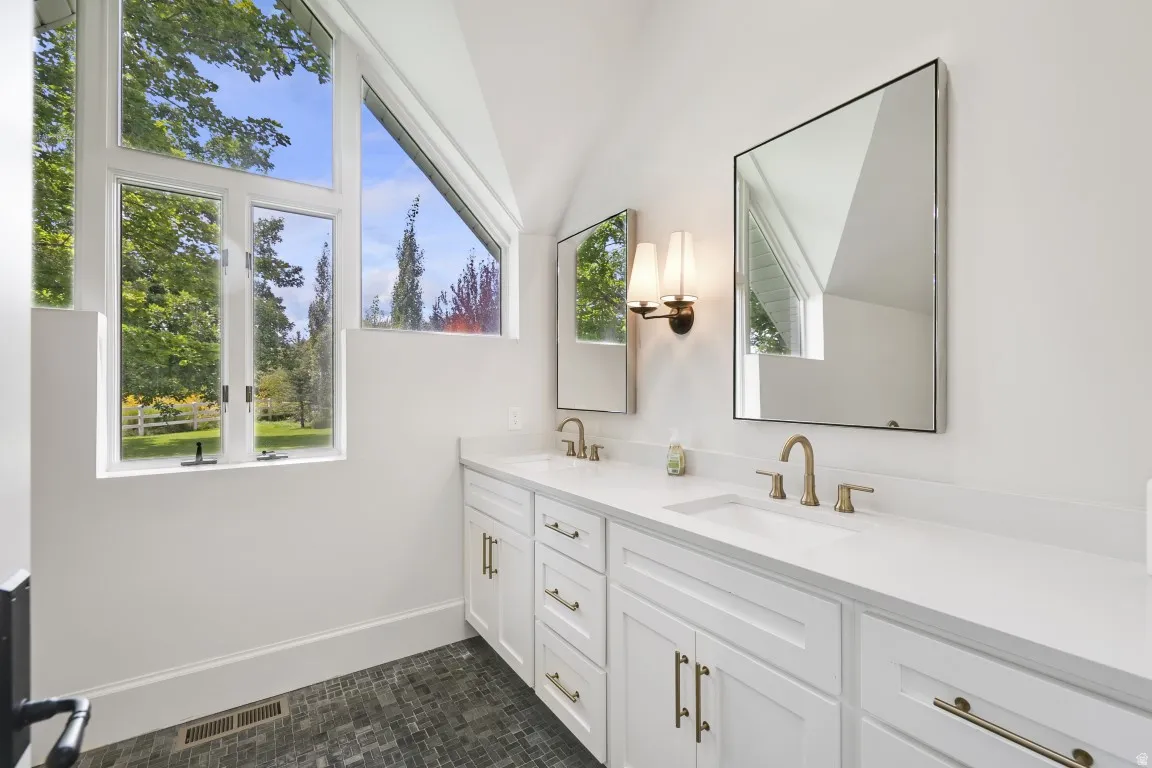 Dual vanity with white cabinetry and integrated sinks, complemented by gold-finish hardware and fixtures