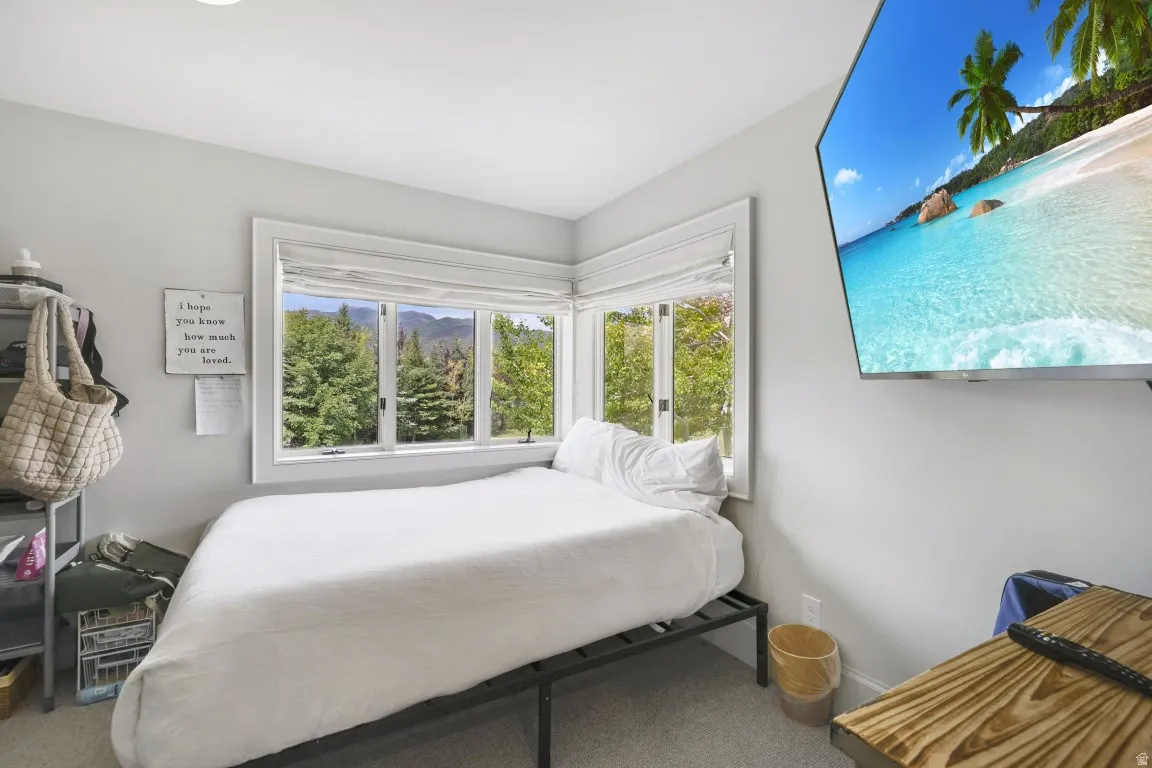 Corner window placement with white trim, recessed ceiling lighting, wall-mounted television, and light gray wall paint