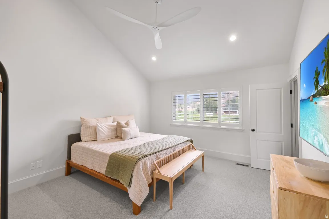 Vaulted ceiling with a contemporary ceiling fan, recessed lighting, white window shutters, and light grey carpeting