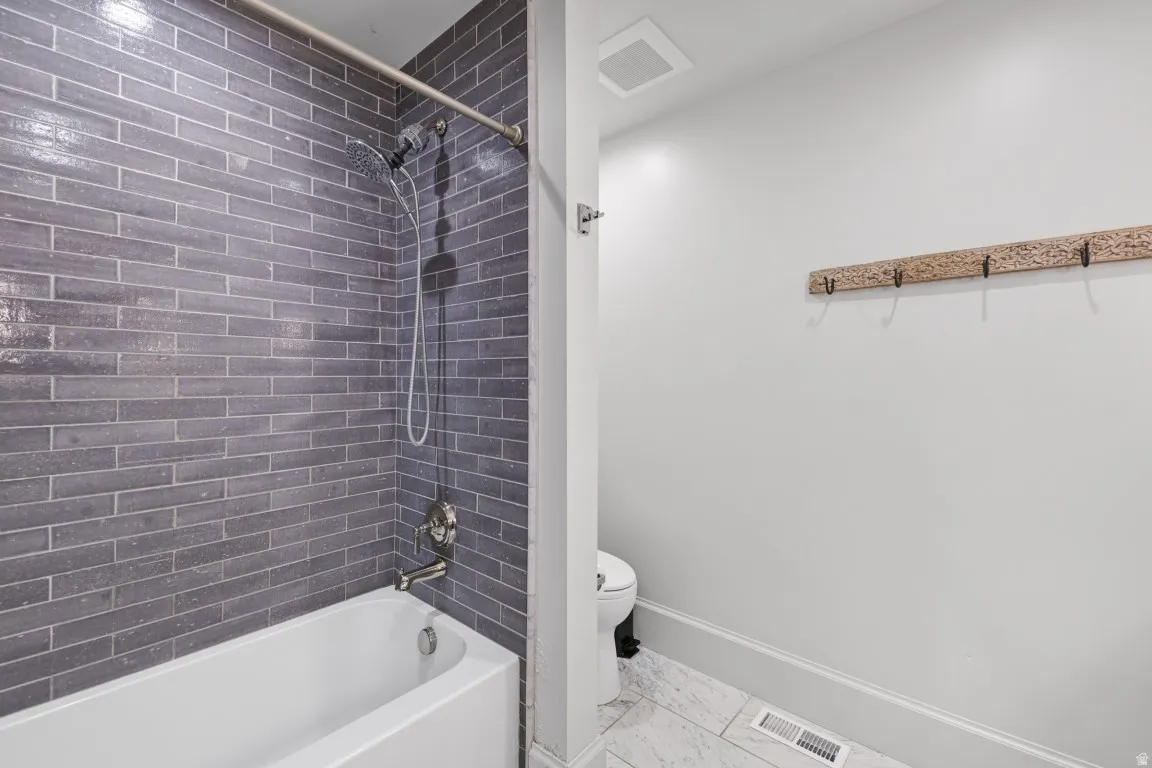Bathtub with subway tile surround, brushed nickel fixtures, and a shower head with handheld sprayer