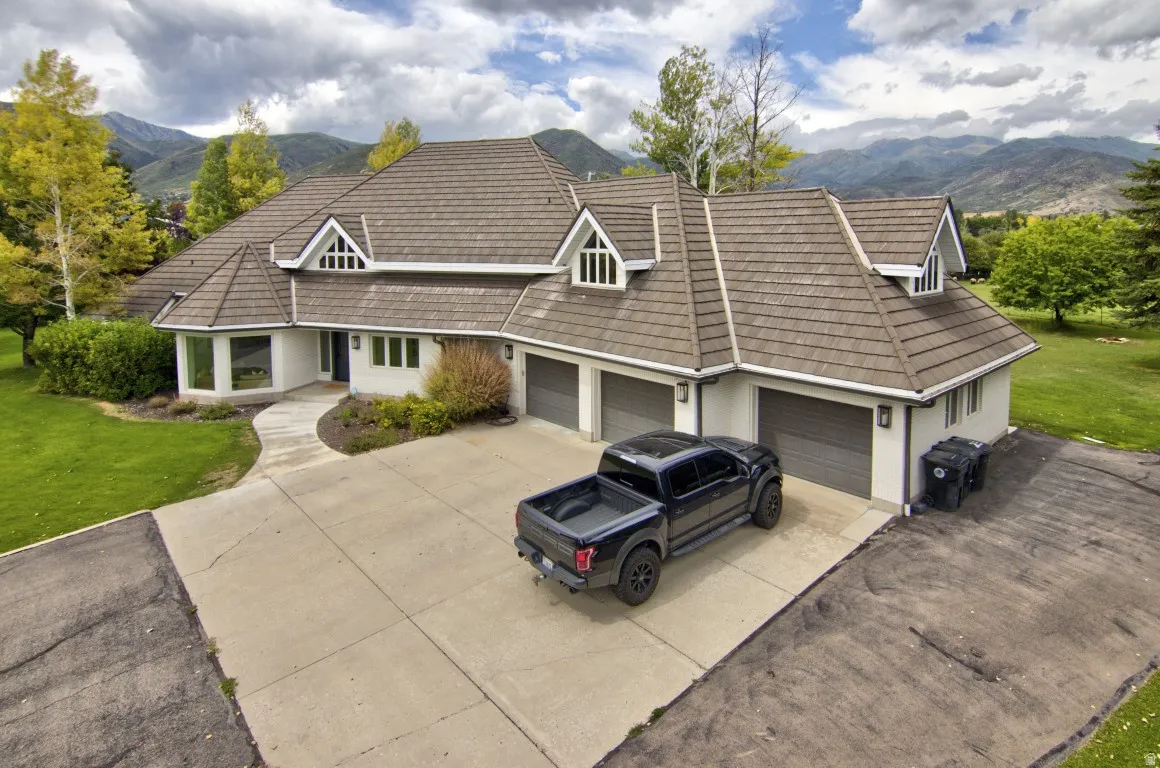 Expansive residence featuring a multi-gabled roofline, three garage doors, and a concrete driveway