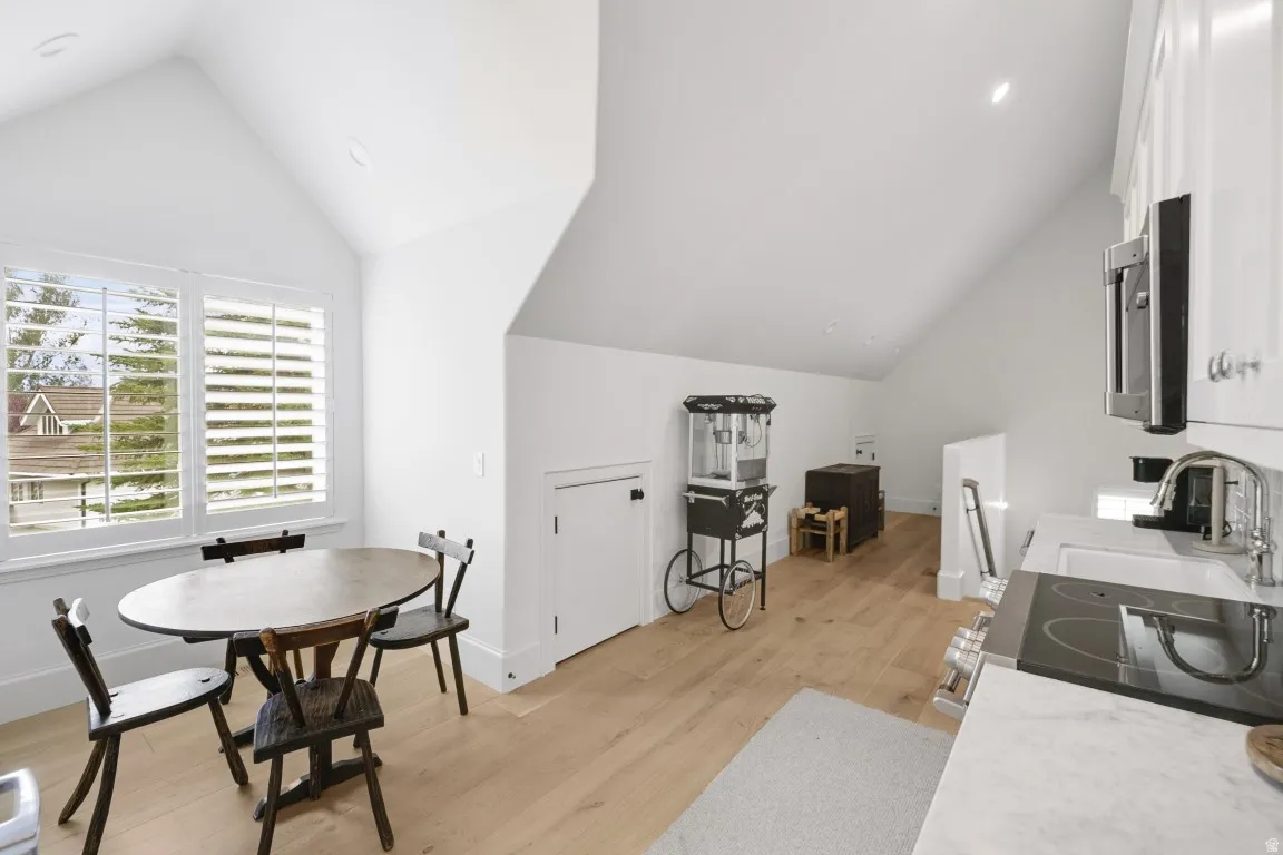 Angled ceilings, light wood-finish flooring, recessed lighting, and white plantation shutters
