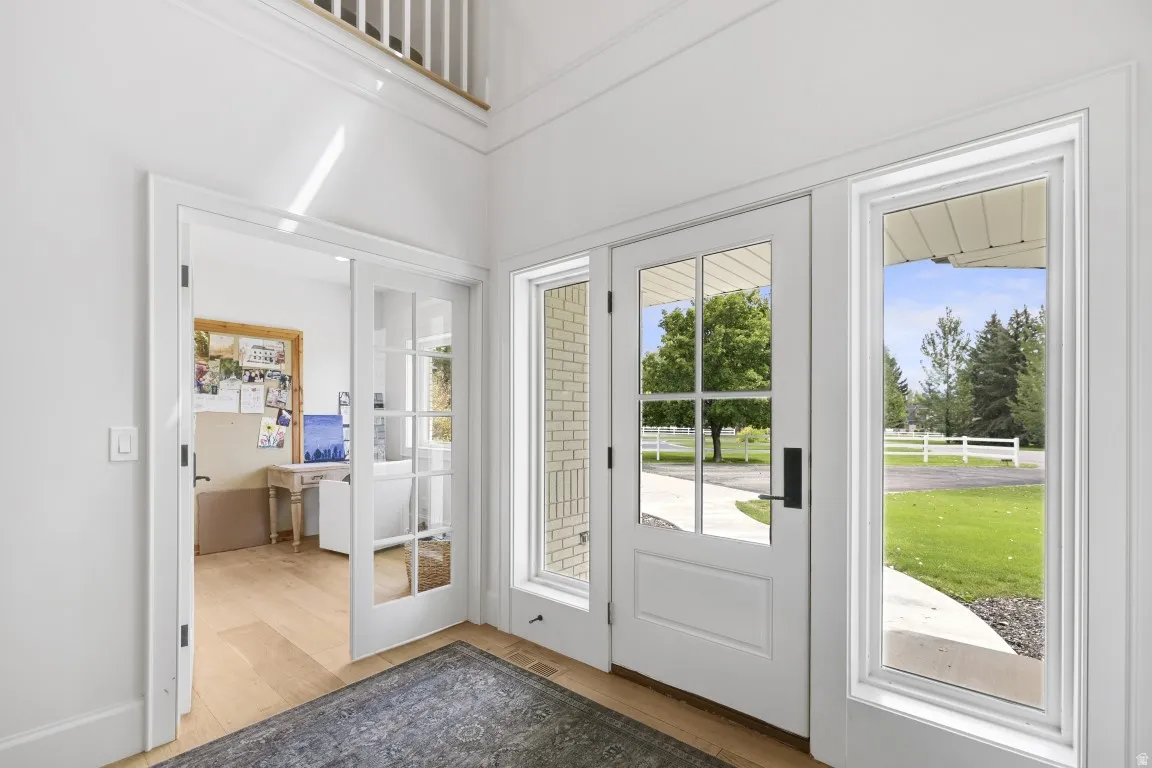Foyer featuring a high ceiling, wood-finish flooring, a paneled entry door with sidelights, and French doors to an adjacent room