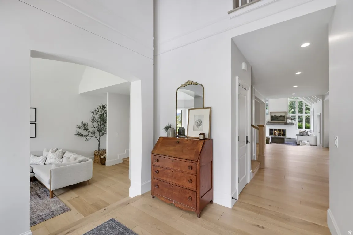 High ceilings, archway, wood-finish flooring, recessed lighting, and a stone-clad fireplace