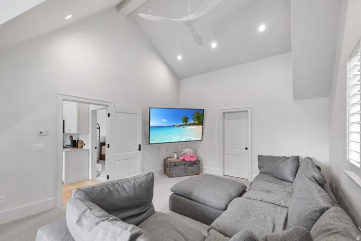 Vaulted ceiling with a ceiling fan, recessed lighting, white double doors, and a window with plantation shutters