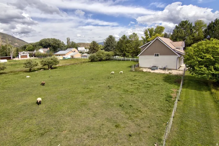 Expansive green space with distant mountain backdrops, mature trees, and a white perimeter fence