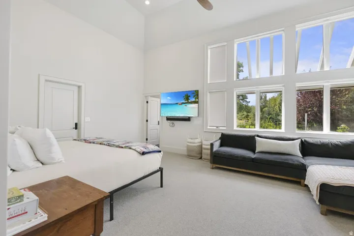 Vaulted ceilings with recessed lighting, expansive multi-pane windows, wall-mounted television, and light-toned carpeting