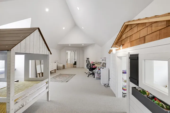 Vaulted ceiling, recessed lighting, and light-toned carpeting