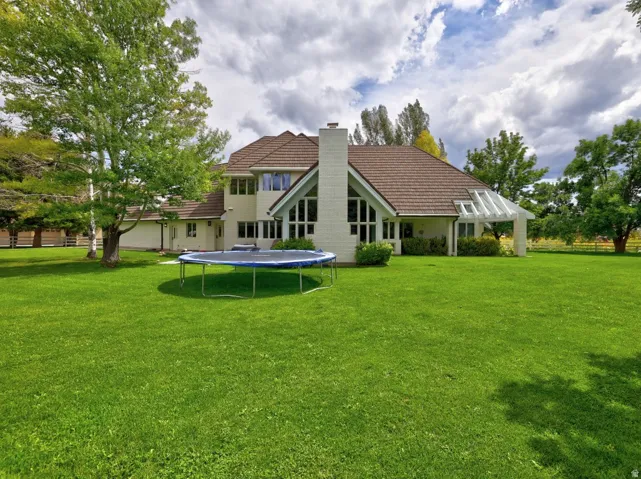 Expansive green lawn with mature trees and a stucco exterior featuring a gabled roof