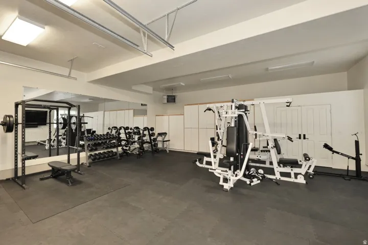 Dedicated fitness space featuring wall-to-wall mirrors, built-in cabinetry, and recessed ceiling lighting