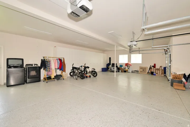 Spacious garage featuring an epoxy floor, multiple windows, and overhead lighting
