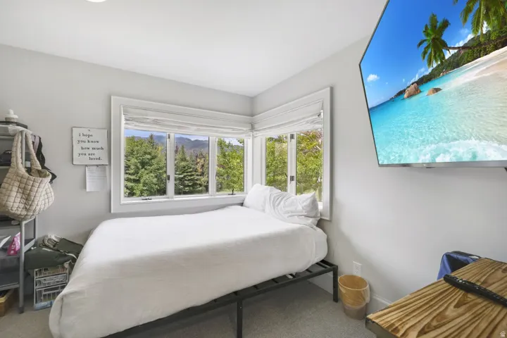 Corner window placement with white trim, recessed ceiling lighting, wall-mounted television, and light gray wall paint